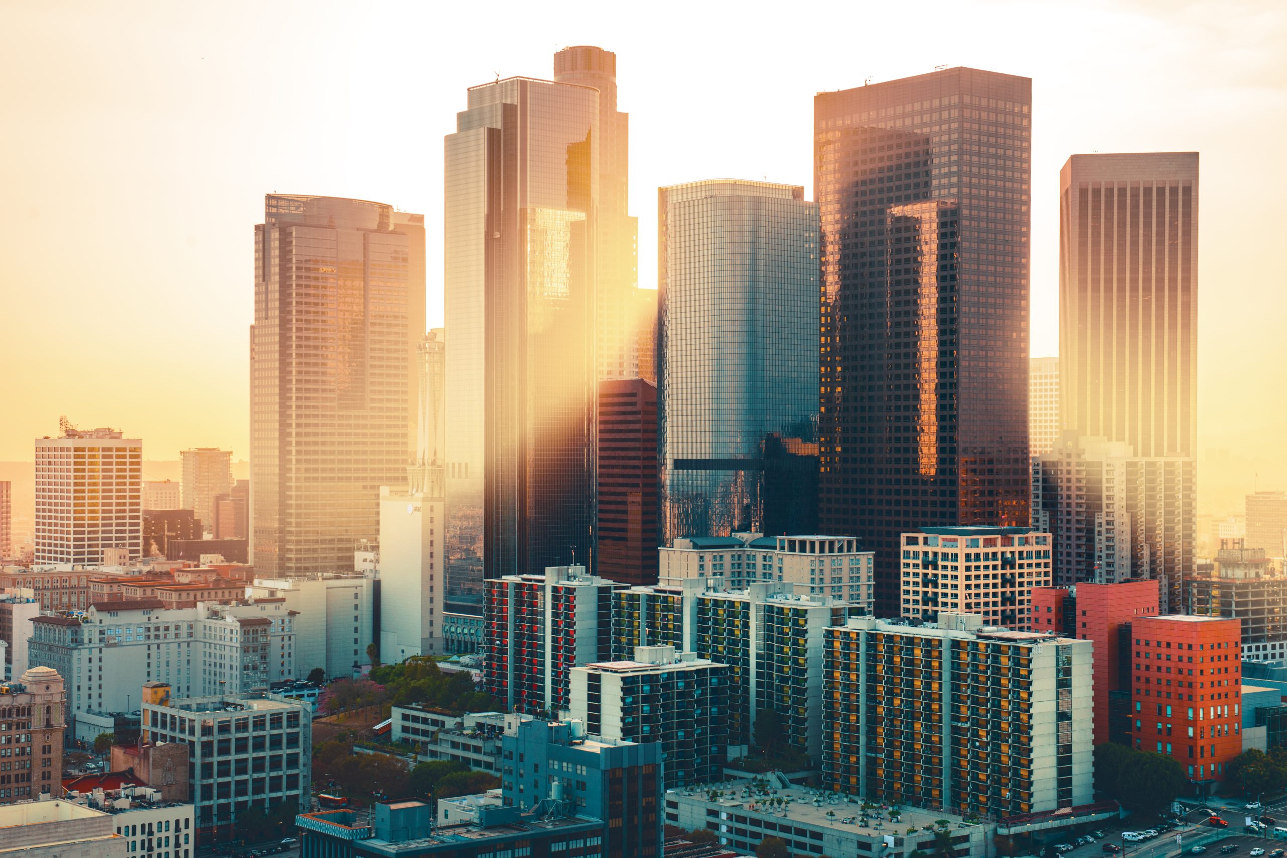 The sun shines through the downtown Los Angeles skyline.