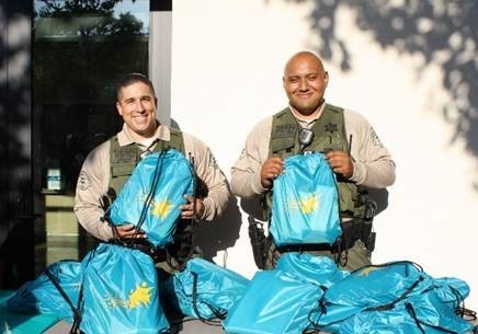 LA County Sheriff deputies distribute bags at a LA County Development Authority event.