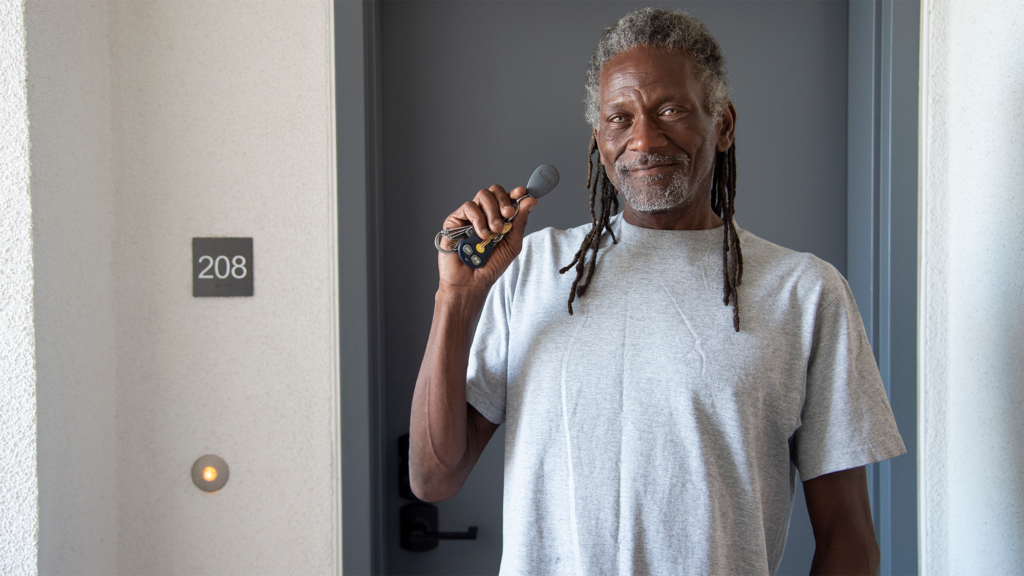 A man holds his keys in front of the door to his home.