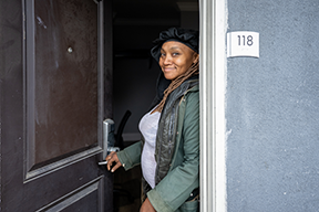A woman smiles as she opens the door to her new apartment after leaving her encampment behind.