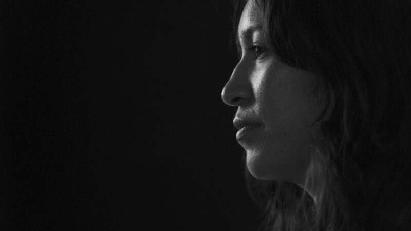 Close up face shot of woman from side profile in black and white with black background