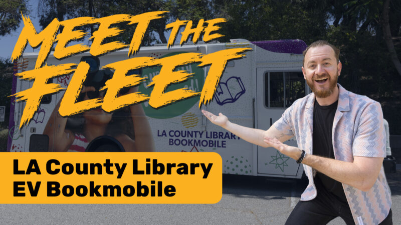 A man gestures towards the LA County Library EV Bookmobile, promoting community access to library services.