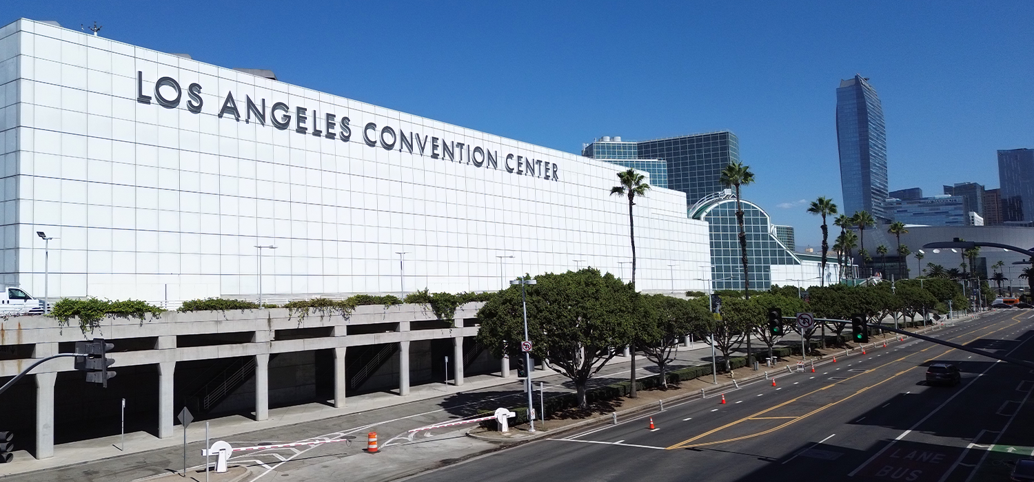 Los Angeles Convention Center exterior with palm trees and clear blue sky, showcasing the city's urban landscape.