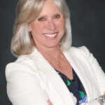 Woman smiling with hair to her shoulders and has her arms crossed